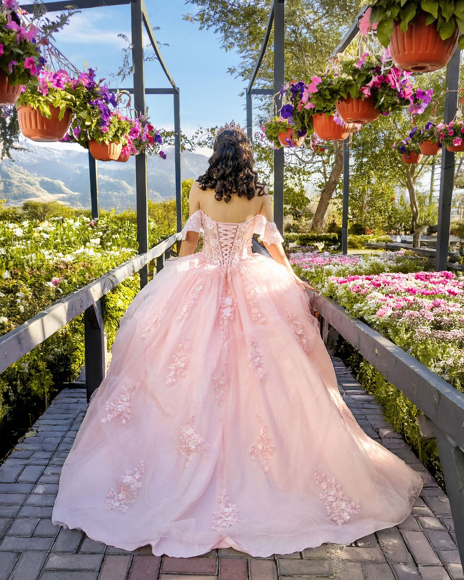 Vista posterior de quinceañera con vestido rosa en jardín