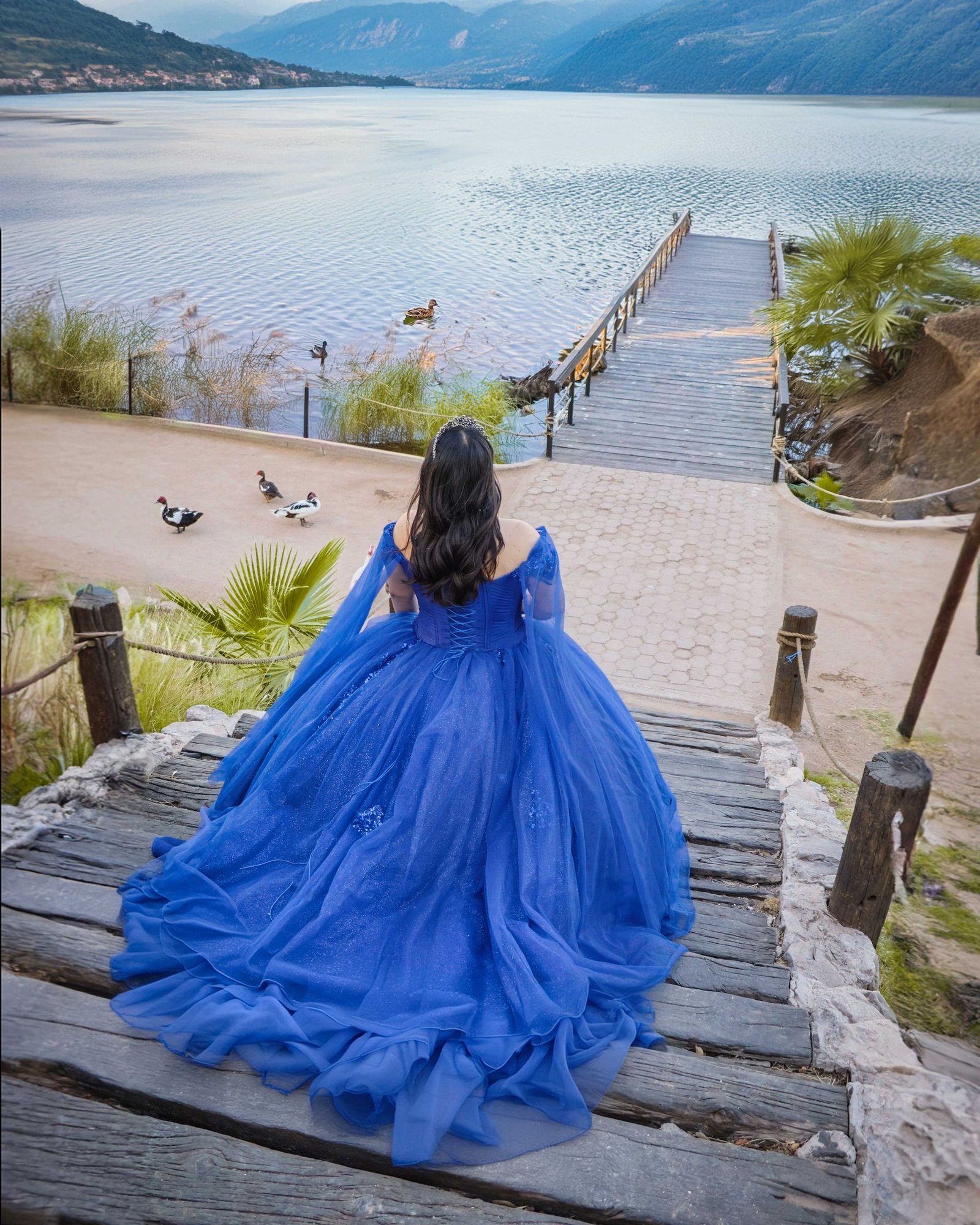 Quinceañera con vestido azul frente al lago