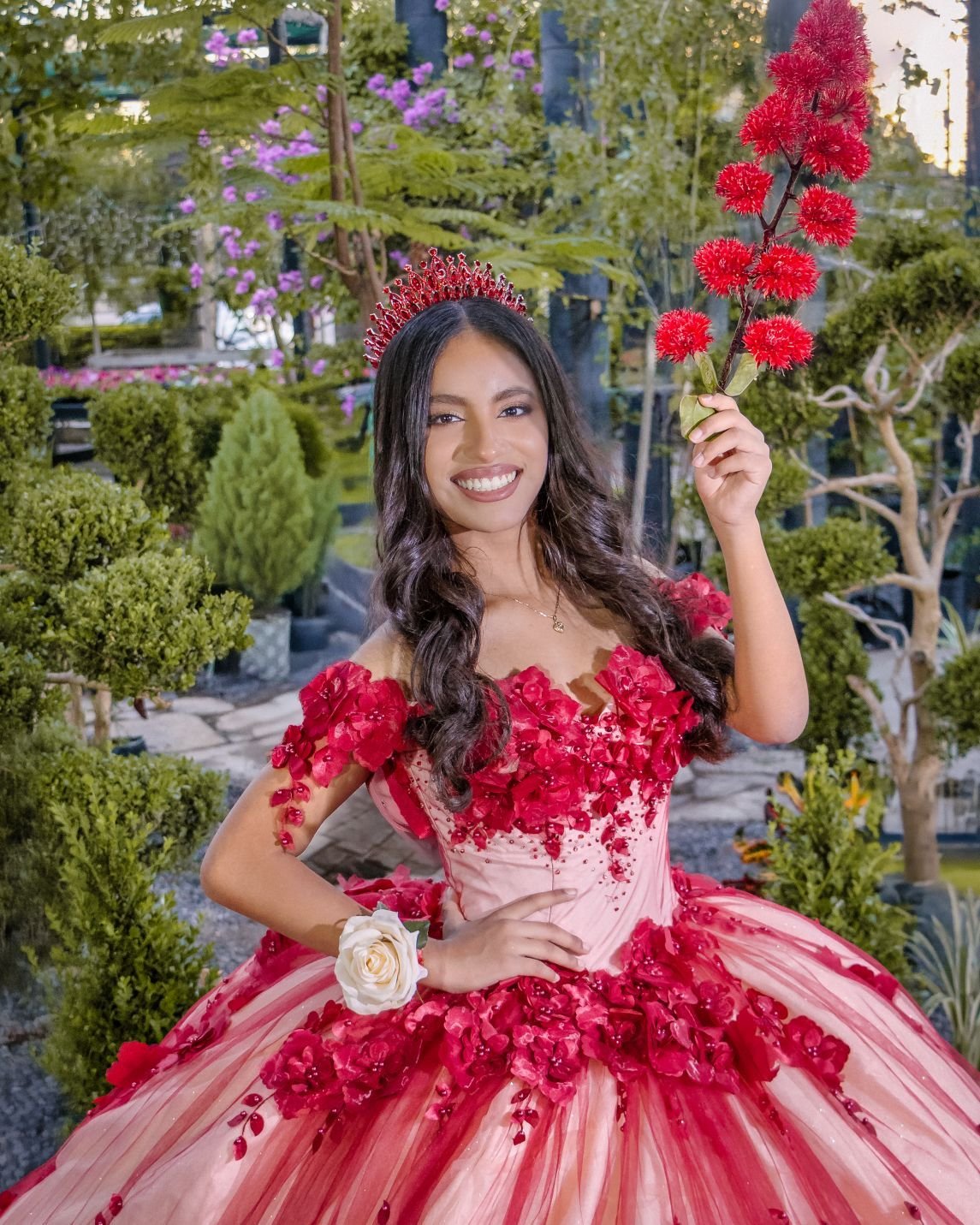 Quinceañera con vestido rojo sosteniendo una rosa